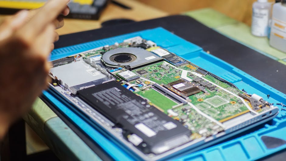 A close-up of a laptop being repaired with visible internal components and tools.