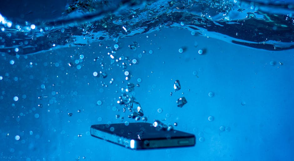 A smartphone submerged in water with bubbles rising around it.